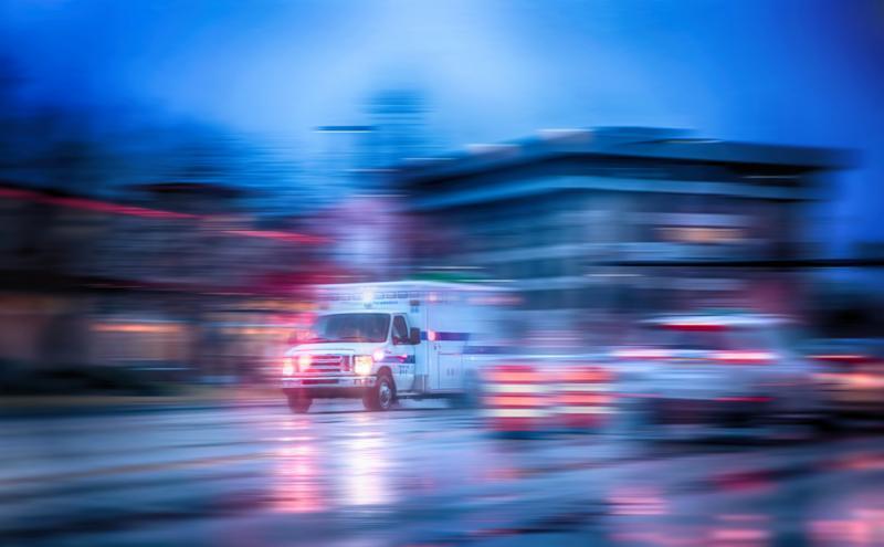 an ambulance racing through the rain on a stormy night with motion blur NO SHARP FOCUS DUE TO RAIN and slow shutter speed with reflections in the road 